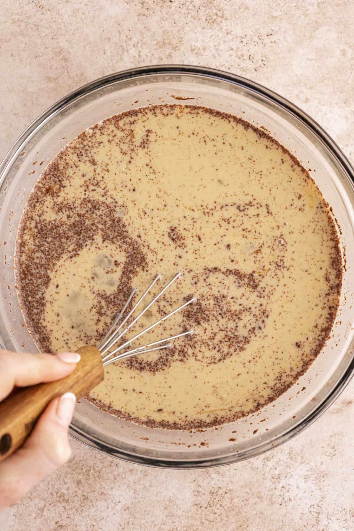 Mischia di crema all'uovo per French Toast mescolata con una frusta in una ciotola di vetro trasparente.