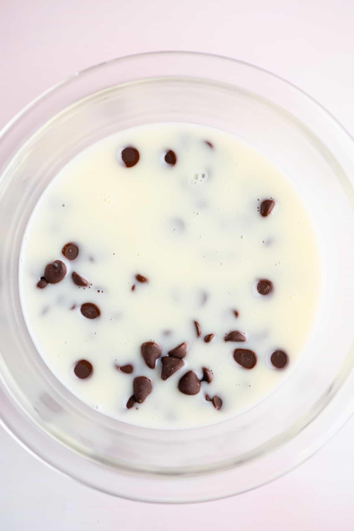 Una miscela di panna fresca e zucchero in una ciotola di vetro con gocce di cioccolato