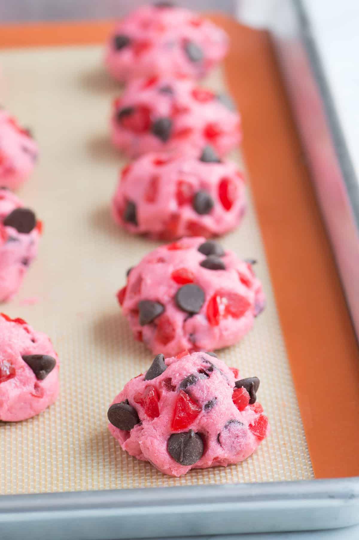 biscotti rosa alle ciliegie maraschino e gocce di cioccolato su teglia prima della cottura