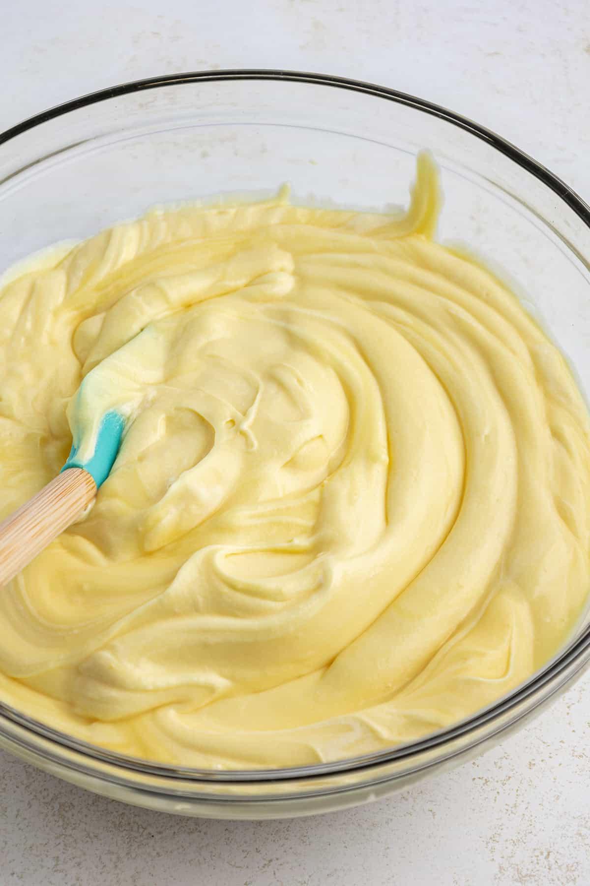Ingredienti per lo strato di budino della torta di terra in una grande ciotola di vetro trasparente con una spatola