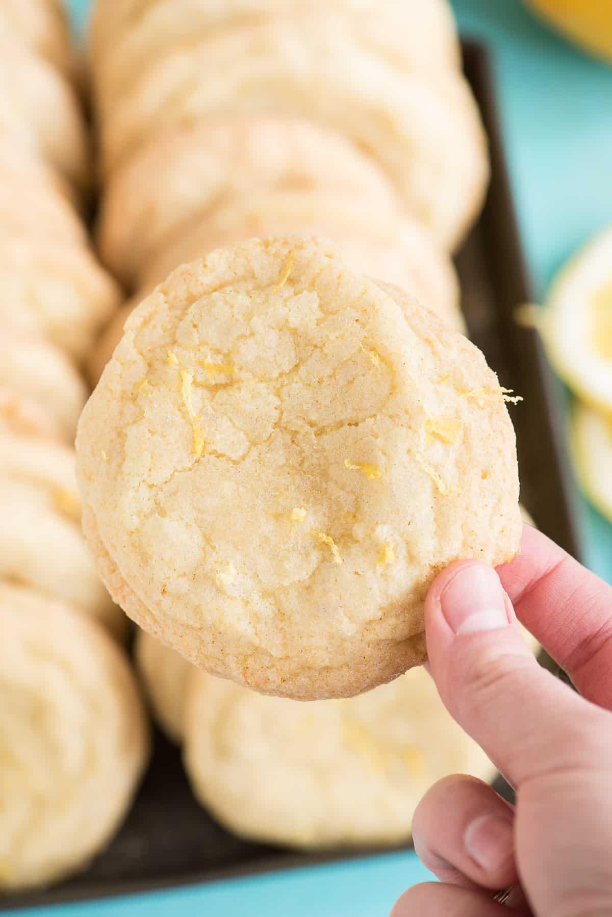 Mano che tiene un biscotto al limone con altri biscotti sullo sfondo