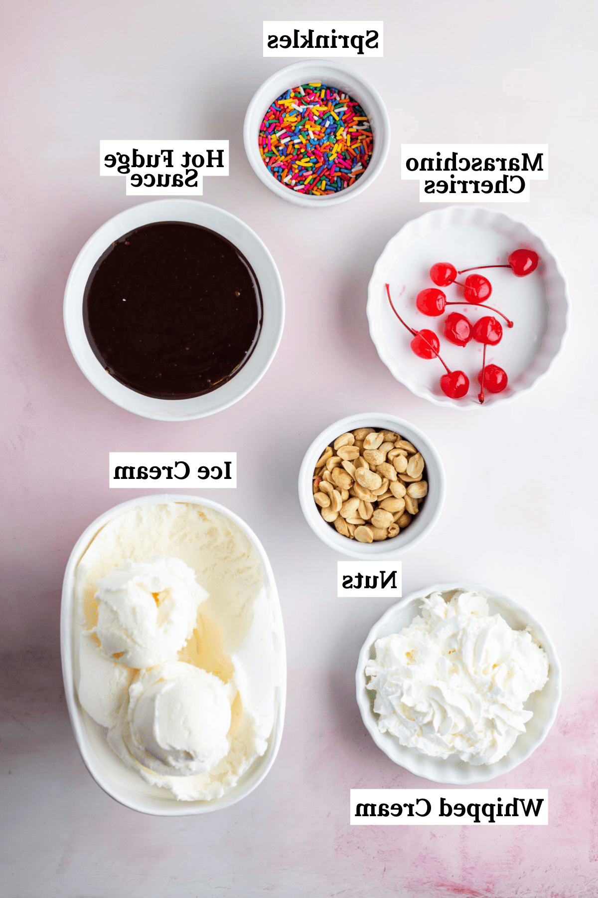 Hot Fudge Sundae 4 Gli ingredienti per un sundae al cioccolato fuso disposti, tra cui una ciotola di codette, una ciotola di salsa al cioccolato fuso, una ciotola di ciliegie al maraschino, una ciotola di arachidi, una ciotola di panna montata e una ciotola di gelato alla vaniglia