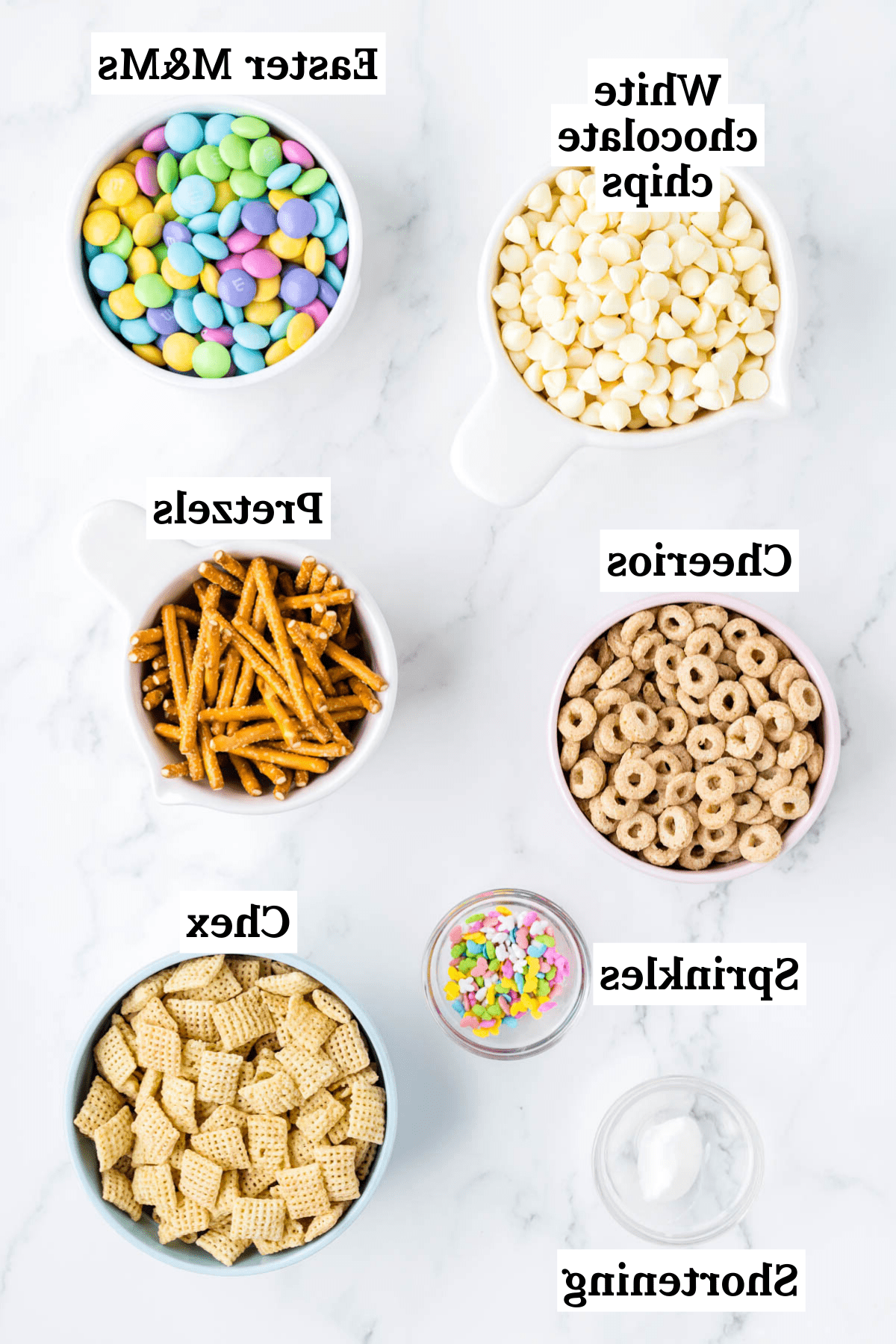 Ingredienti per 'Bunny Bait' inclusi cereali Chex di riso, Cheerios al miele e noci, bastoncini di pretzel, M&M's di Pasqua, gocce di cioccolato bianco, burro vegetale e codette pasquali