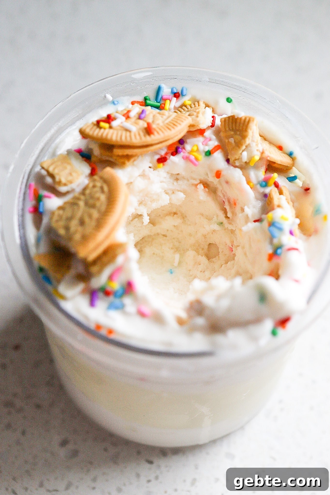 Bite shot out of the protein sugar cookie ice cream with golden oreos and sprinkles on top.