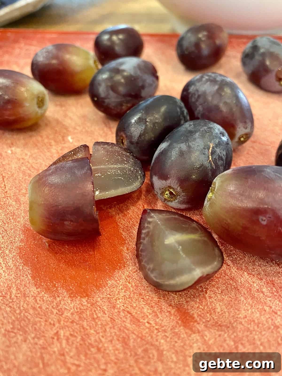Grapes sliced in half on a cutting board.