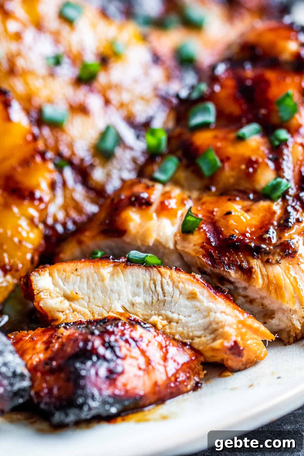 Sliced pineapple chicken on a platter with close up of slice.