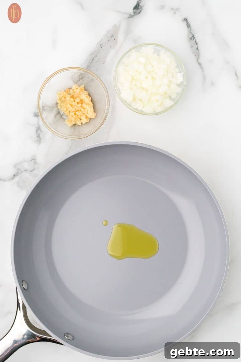 a skillet with olive and a bowl of onion and garlic on the side.