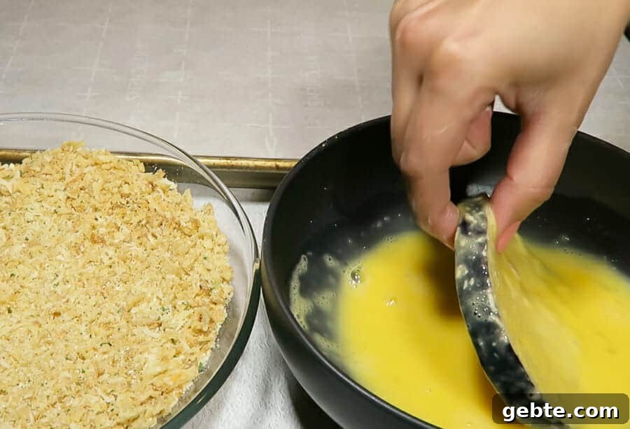 eggplant rounds being dipped in egg mixture for the crispy eggplant parmesan