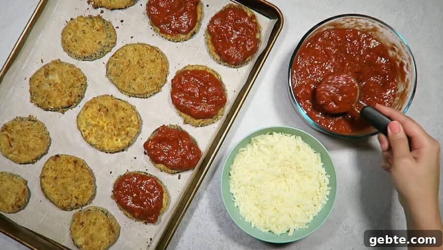 crispy eggplant parmesan being topped with homemade marinara sauce