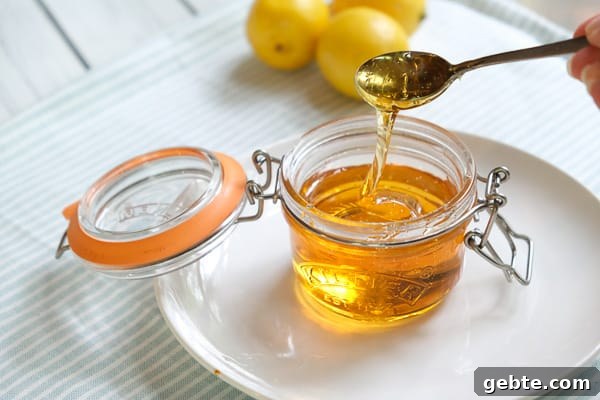 A small jar of golden syrup with lemons in the background