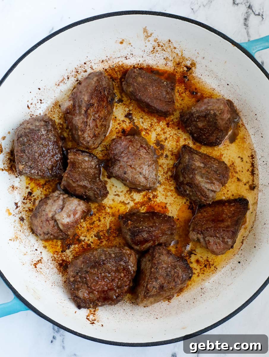 Hearty Oven-Braised Beef Stew Recipe for Comforting Dinners 5 Beef cooking in a dutch oven.