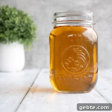 a jar of vanilla syrup by a plant.