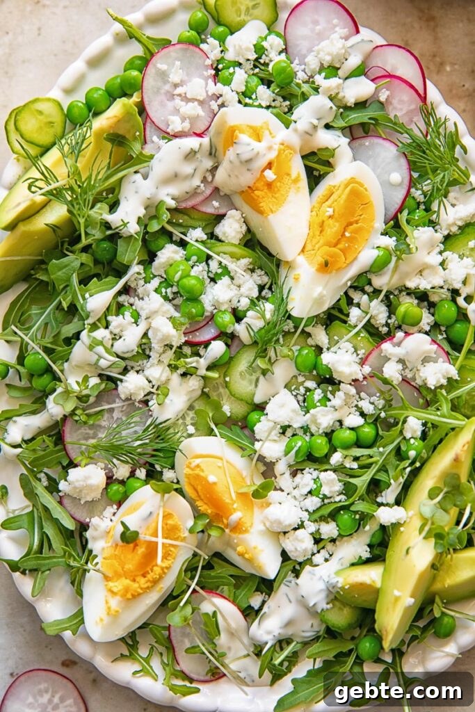 Spring Pea & Arugula Salad with Creamy Dill Dressing 2 top down view of a salad on a platter topped with boiled egg wedges, peas, feta and avocado