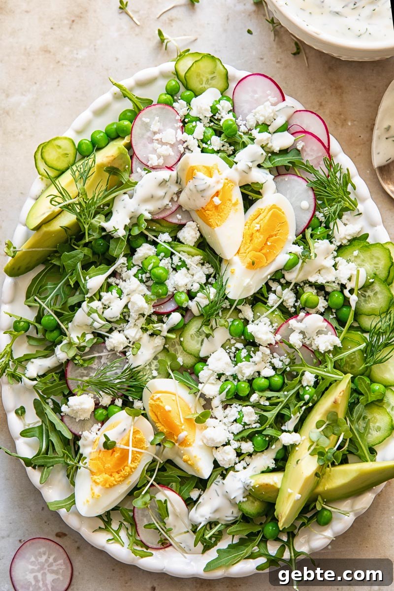 Spring Pea & Arugula Salad with Creamy Dill Dressing 4 top down view of a salad topped with green peas, boiled eggs, sliced radishes and avocado