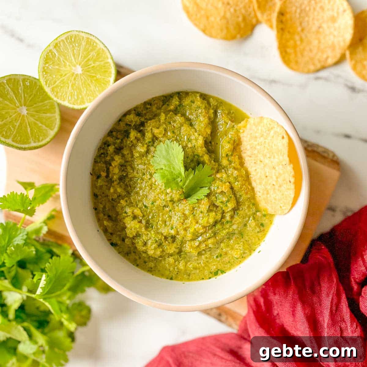 7 Most Popular Salsas and How to Use Them 4 A bowl of serrano salsa is shown with limes, chips, cilantro, and a red linen.