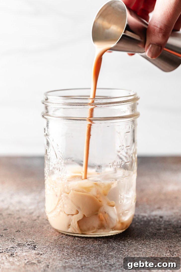 Pumpkin Spice Espresso Martini Recipe for Fall Cocktails 4 Irish cream being poured into a jar.