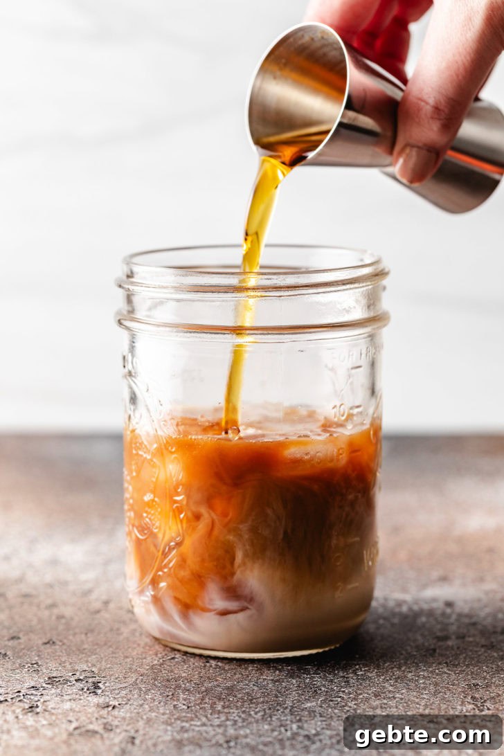 Pumpkin Spice Espresso Martini Recipe for Fall Cocktails 5 Pumpkin spice coffee syrup being poured into a jar.