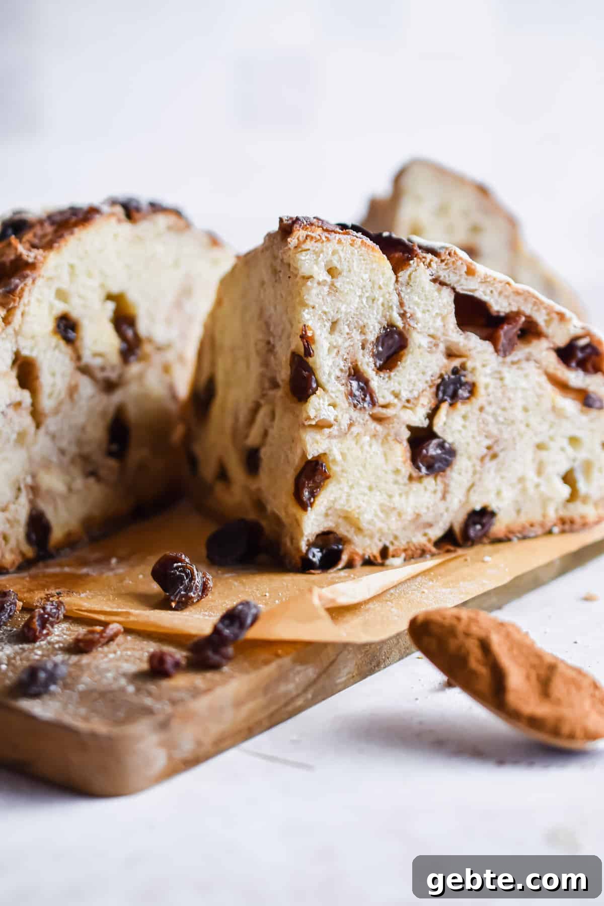 A chunk of the sourdough cinnamon raisin bread is in front of the other half of bread.