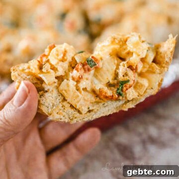 holding a piece of new orleans style crawfish bread, showing crawfish and cheesy sauce.