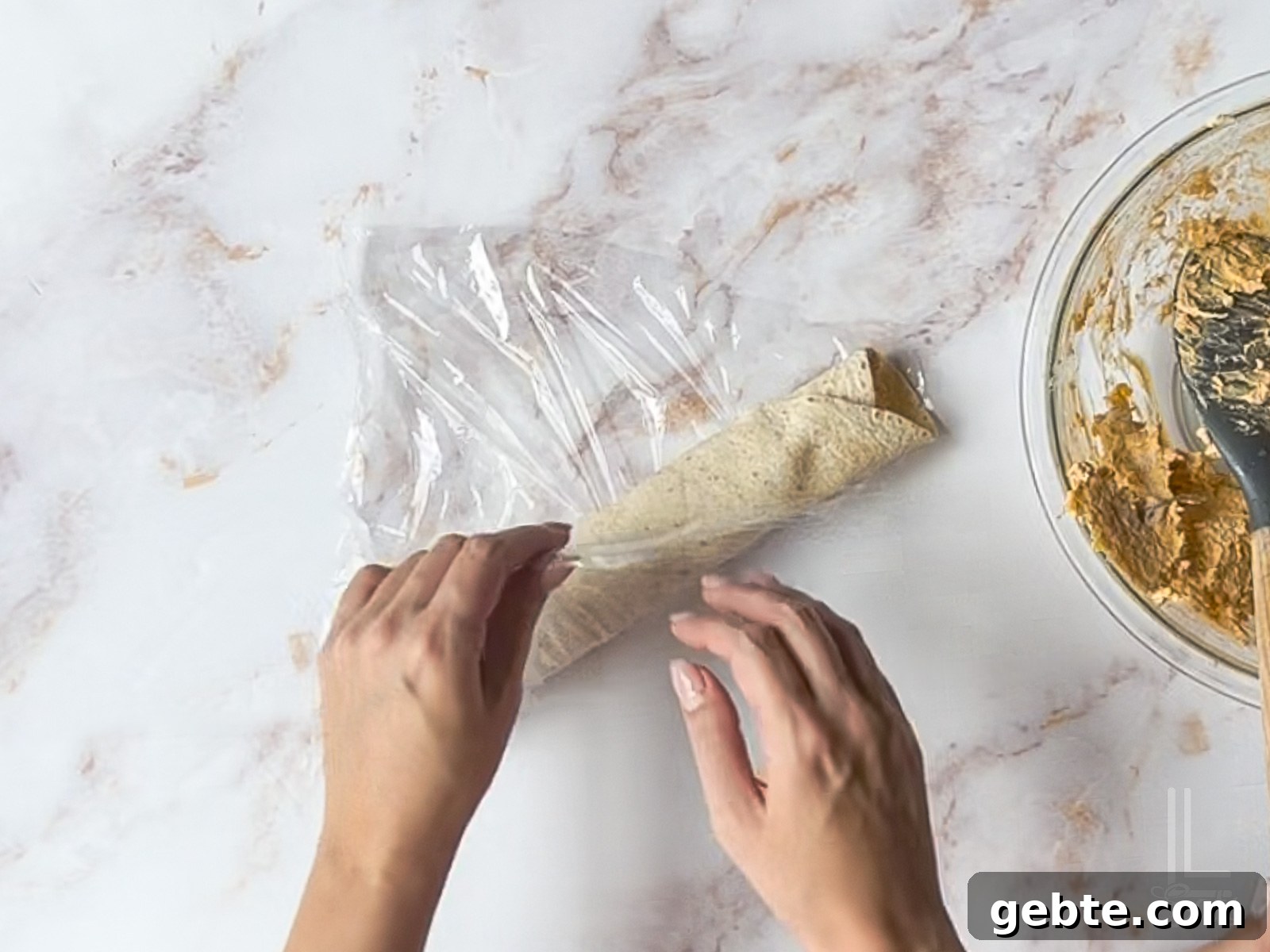 wrapping tortilla roll-up in plastic wrap.