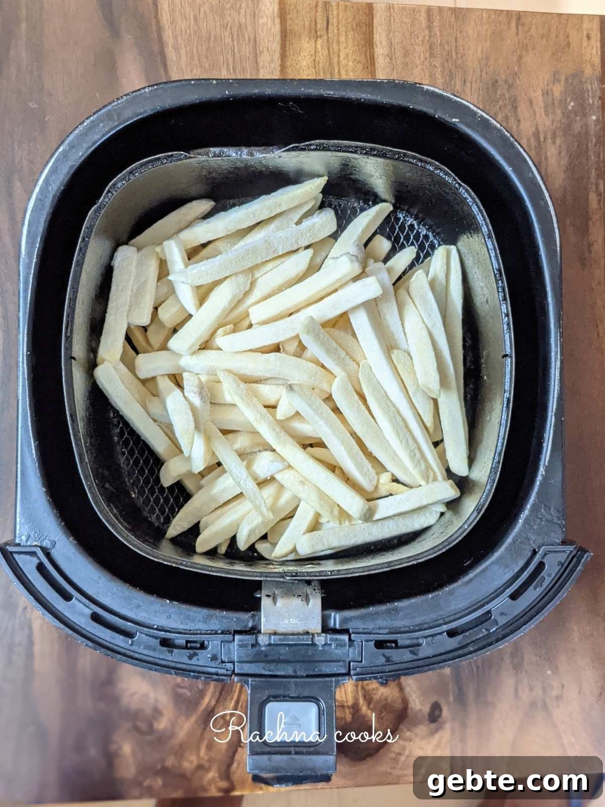 Frozen french fries laid in air fryer basket ready for air frying.