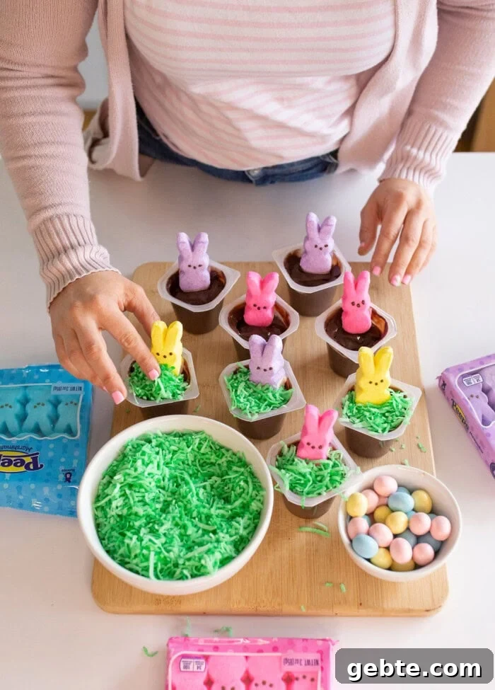 Peeps bunnies in pudding cups with green shredded coconut around the bunnies.