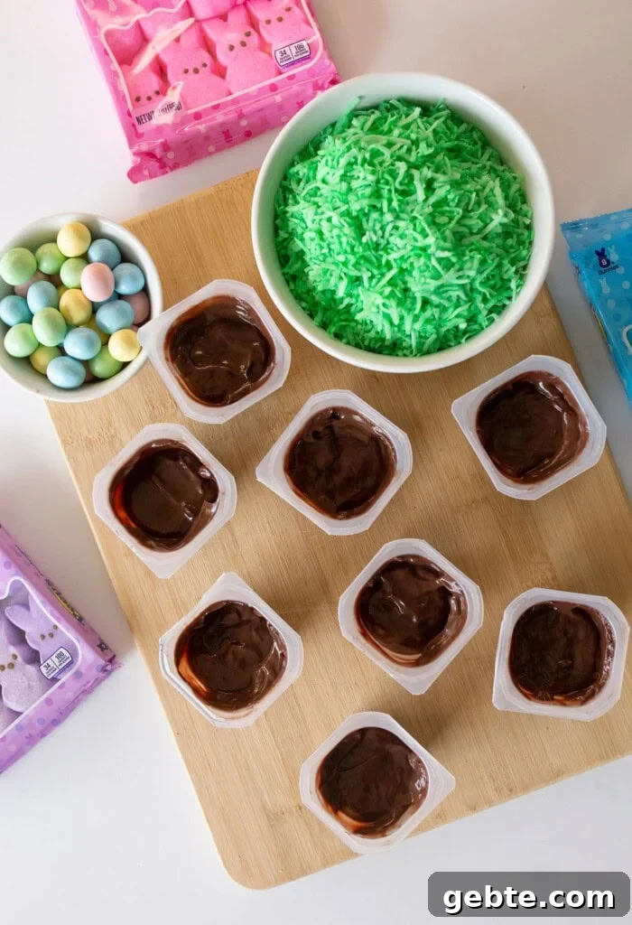 The ingredients, pudding cups, shredded green coconut, chocolate easter eggs, and peeps bunnies. All the ingredients to make easter bunny pudding cups.
