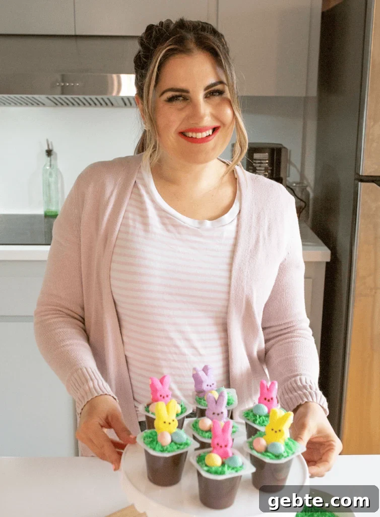 Melissa Johnson holding finished easter bunny pudding cups on a white cake stand.