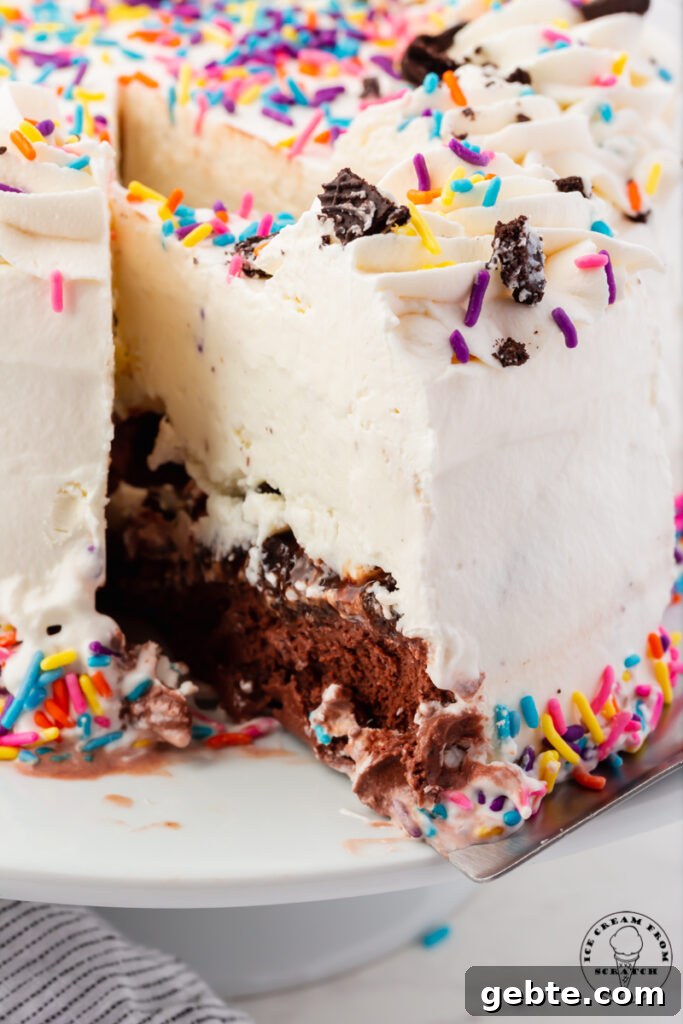 a slice of ice cream cake being pulled away from the whole cake with a cake server. Inside the cake is a layer of chocolate ice cream, cookies, and vanilla ice cream.
