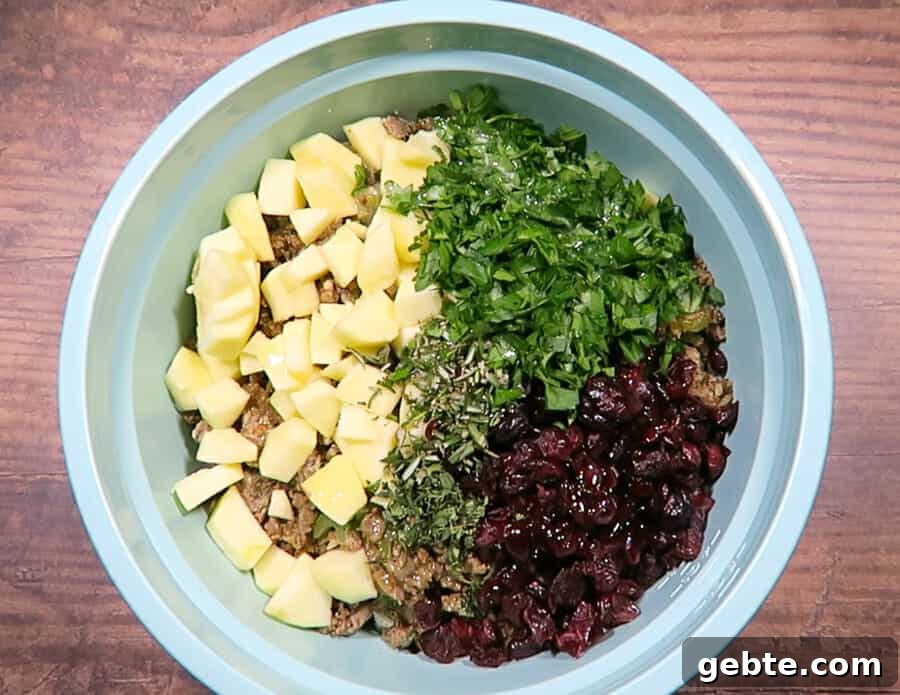Sausage, Apple & Cranberry Stuffing with Fresh Herbs 7 ingredients all in a bowl for the sausage stuffing
