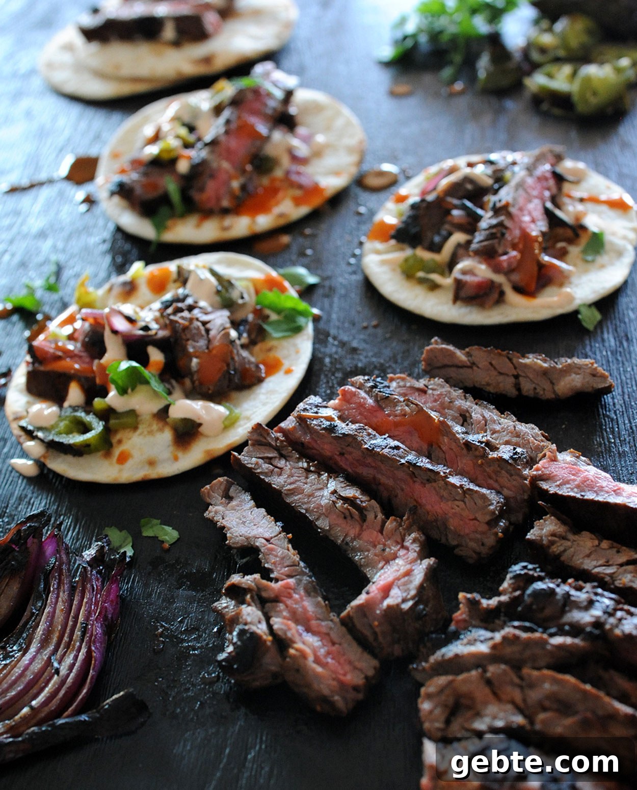 Grilled Skirt Steak Tacos with Charred Lime and Cilantro 10 grilled skirt steak tacos on black background