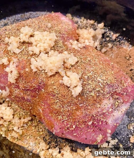 Pork Roast in bottom of slow cooker with spices and garlic