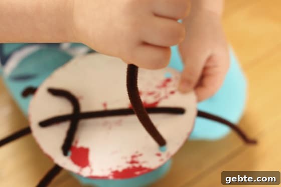 threading pipe cleaner "legs" through holes punched in paper plate