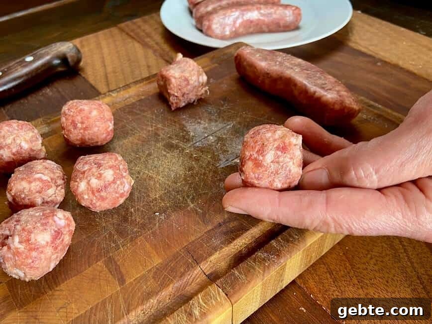 One-Pot Sausage and Meatball Pasta Skillet 7 Hand holding an uncooked meatball.