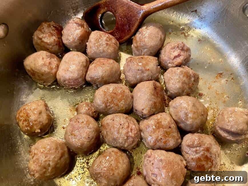 One-Pot Sausage and Meatball Pasta Skillet 8 Cooking meatballs in a pan.