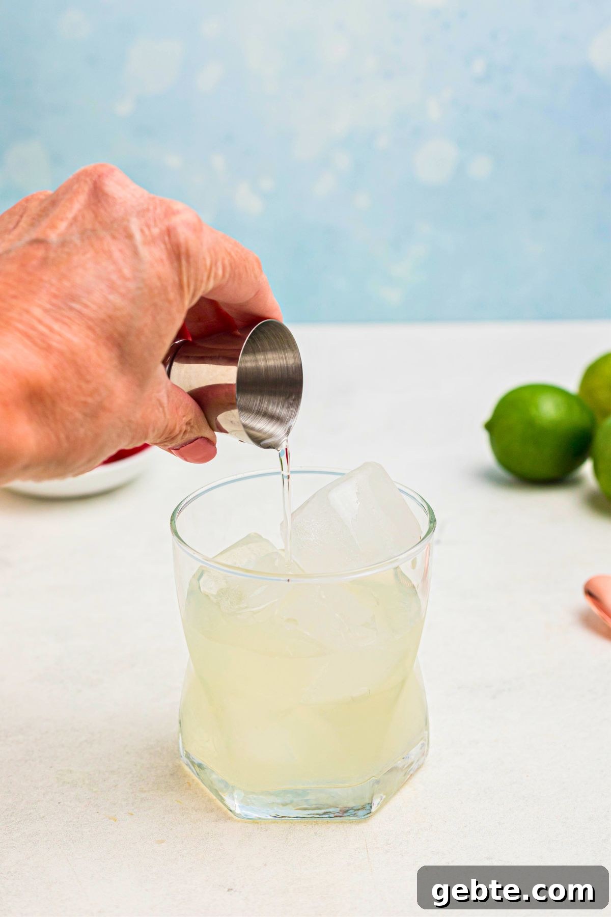 How to Make a Classic Mai Tai Cocktail at Home 4 Clear liquid being poured into a clear glass, filled with ice.