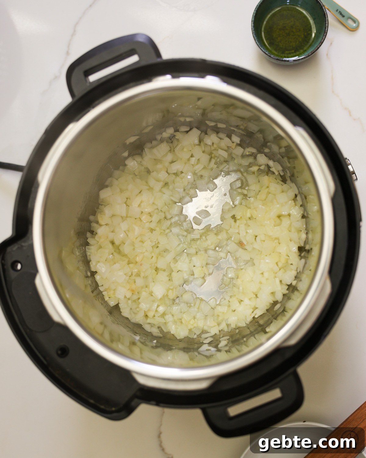 Creamy Instant Pot White Beans with Lemon and Rosemary 4 Onions sautéing in an instant pot.