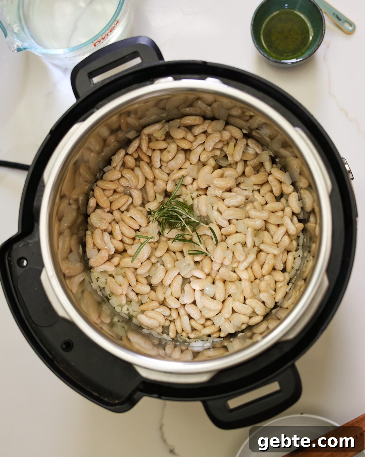 Creamy Instant Pot White Beans with Lemon and Rosemary 5 Beans and fresh rosemary in Instant Pot.