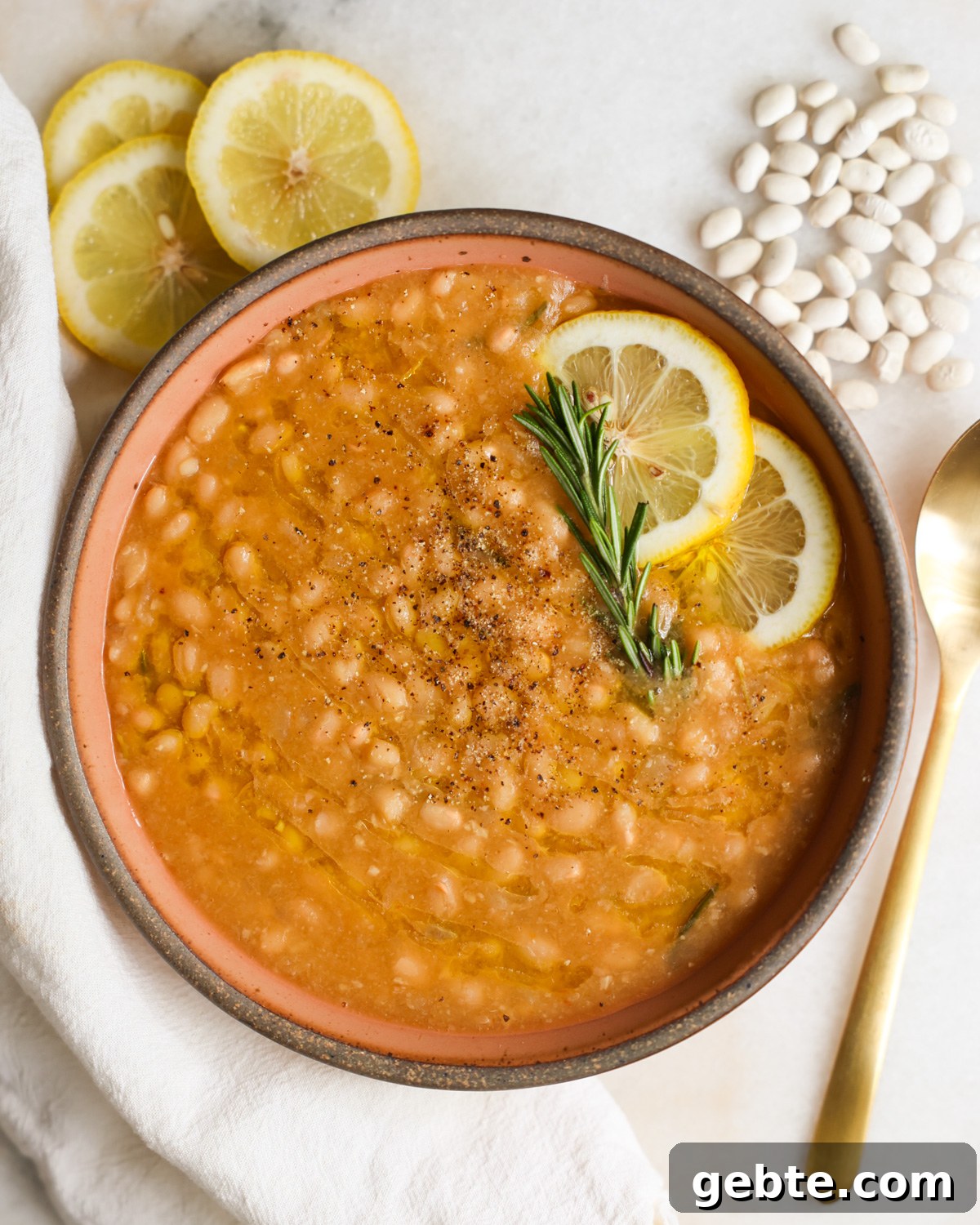 Creamy Instant Pot White Beans with Lemon and Rosemary 10 A bowl of Instant Pot white beans with lemon and rosemary garnish.