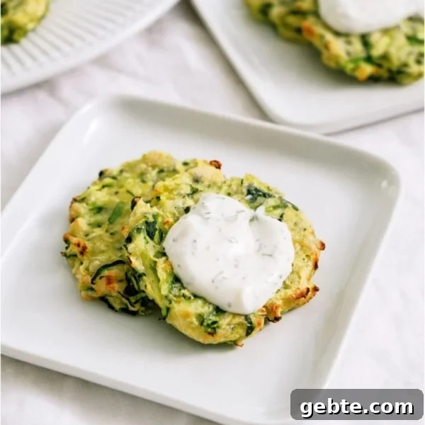 Crispy Air Fryer Zucchini Fritters on a plate topped with dill sour cream dip.