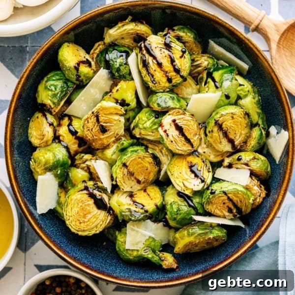 A large bowl of Crispy Air Fryer Brussel Sprouts drizzled with balsamic glaze with a wooden spoon on the side.