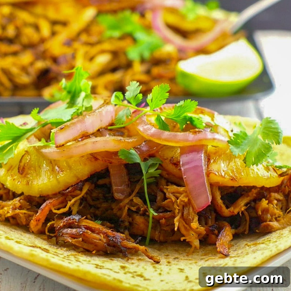 pineapple carnitas on a white surface with tray of more carnitas in the background
