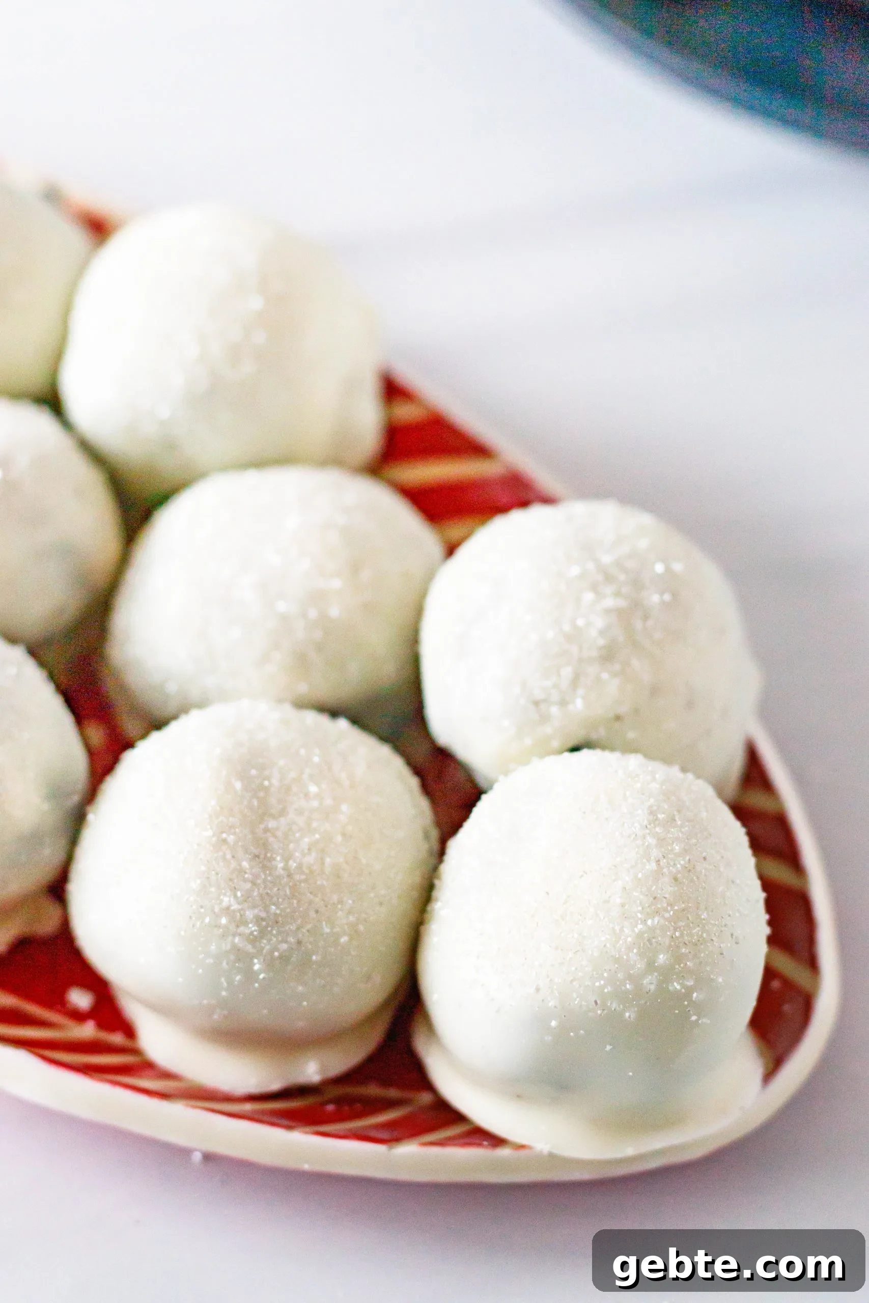 angled picture of sparkling chocolate cookie truffles sitting on a red and white striped tray
