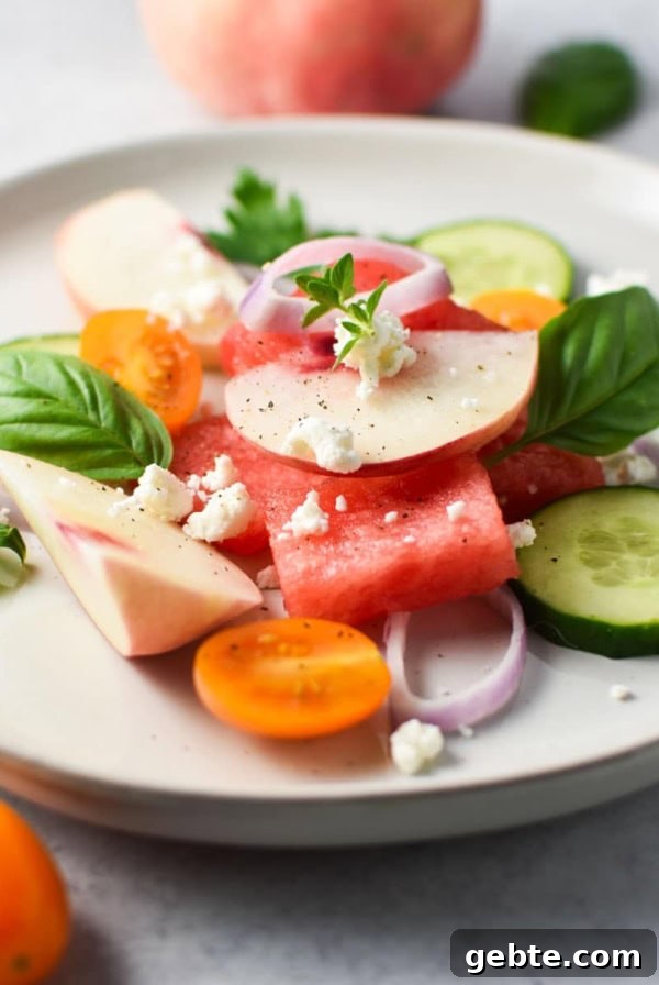 Watermelon peach salad topped with basil and cucumber.