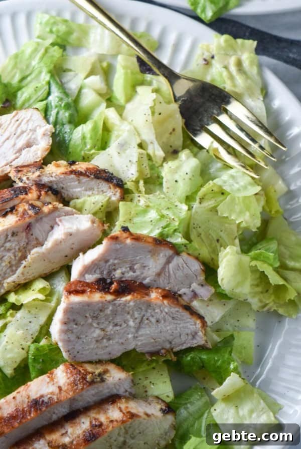Caesar salad next to a cup of caesar salad dressing.