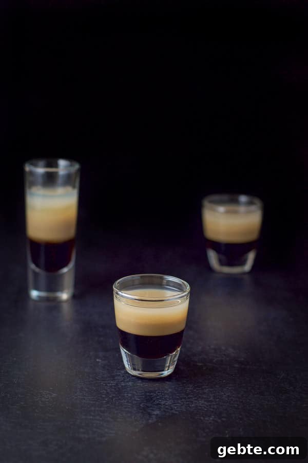 Short glass with the layered shot in front of the tall glass and another short glass