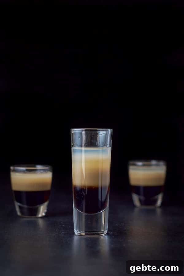 Vertical view of the tall glass filled with the peppermint shot with two other glasses behind it