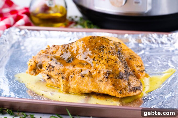 A turkey breast that was cooked in the Instant Pot, placed on a baking sheet and covered in a butter mixture.