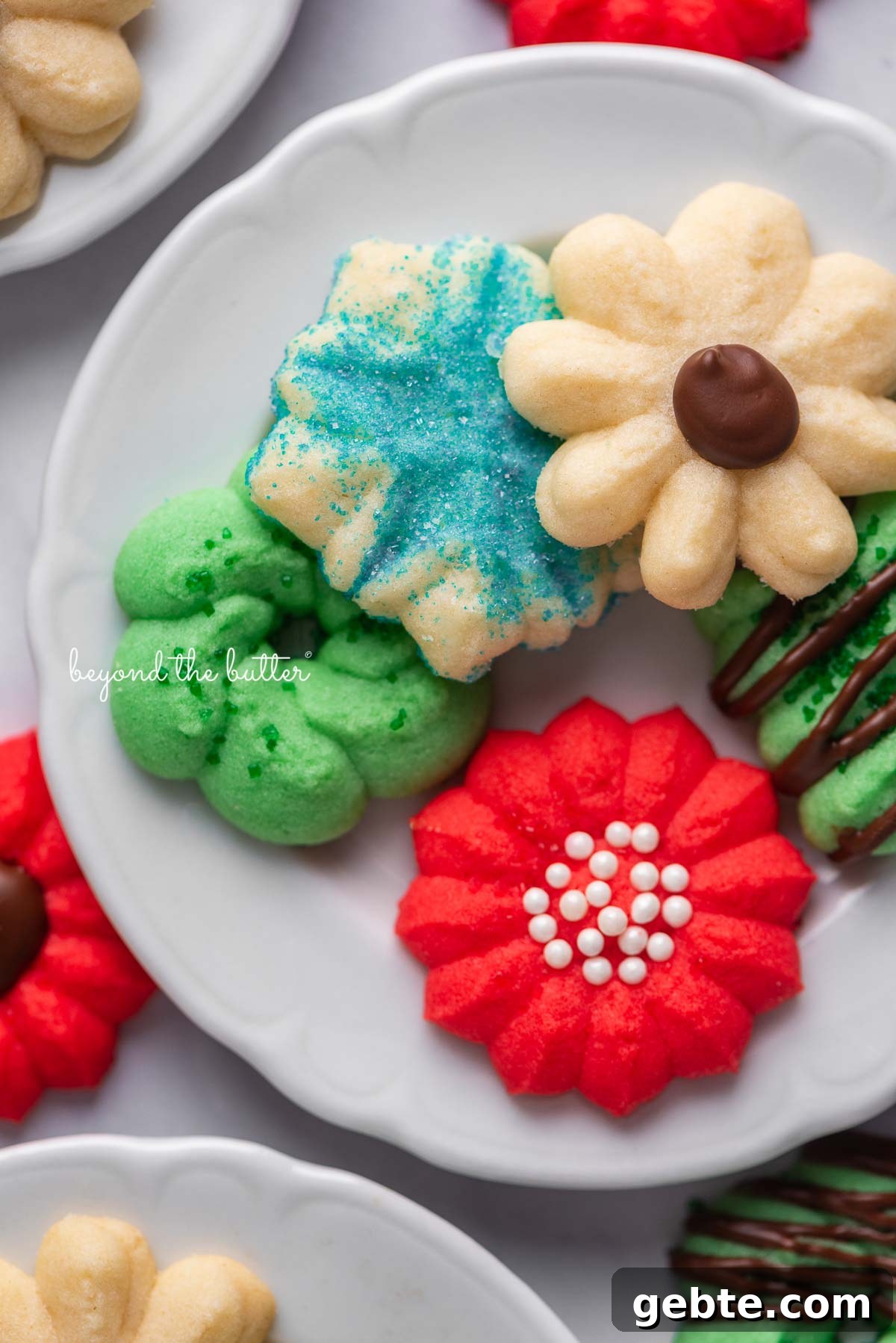 Tiny dessert plates with classic spritz cookies on a white marble background | © Beyond the Butter®