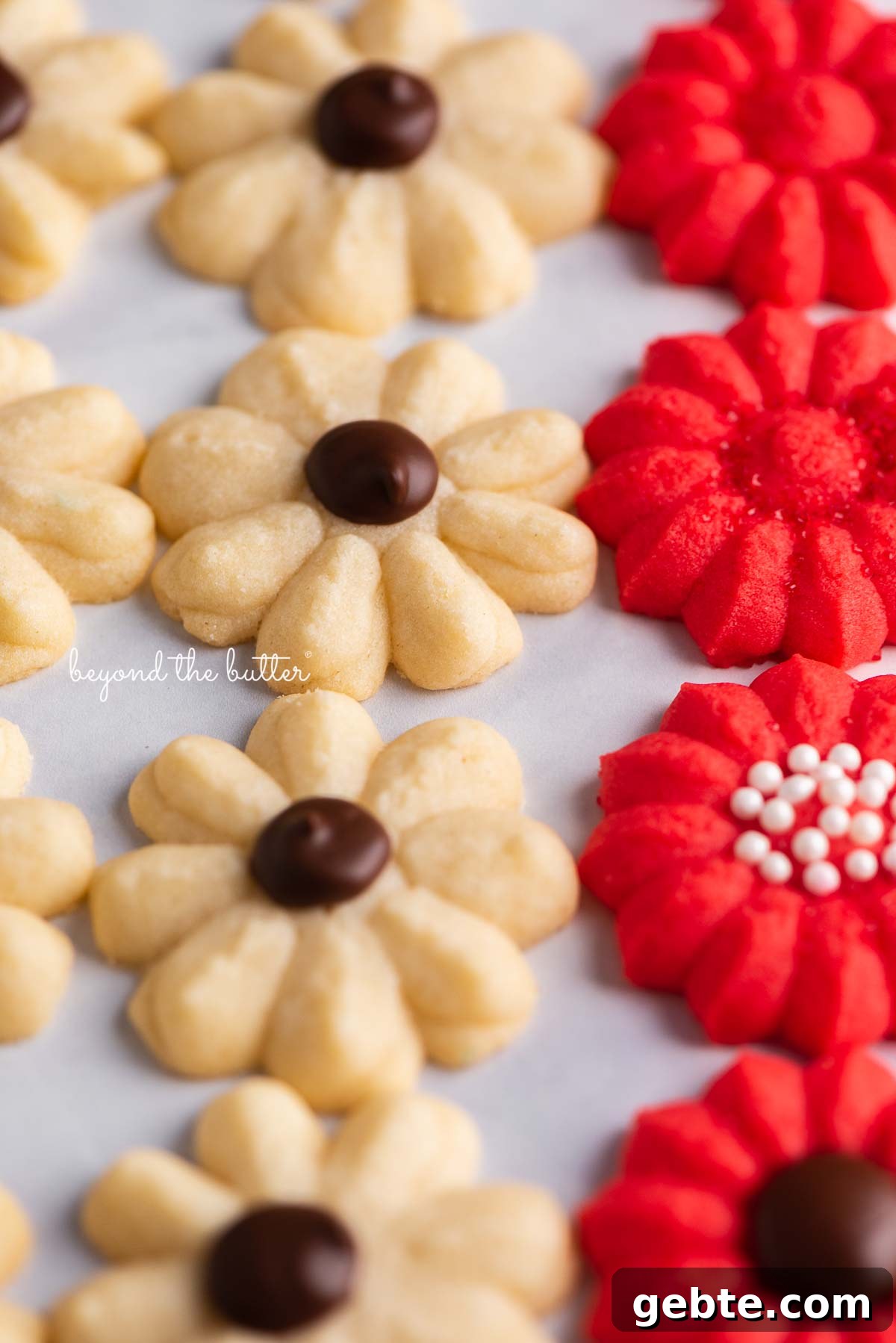 Decorated classic buttery spritz cookies lined up on a white marbled background | © Beyond theButter®